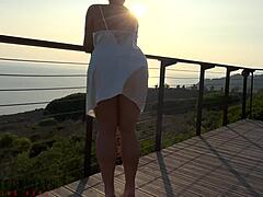 Femeia matură într-o rochie albă face sex în aer liber pe balcon