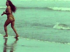 Сексуальная женщина-богиня тренируется с подвязками на пляже в горячей сцене